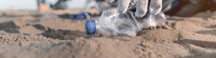 People picking up a bottle on the beach