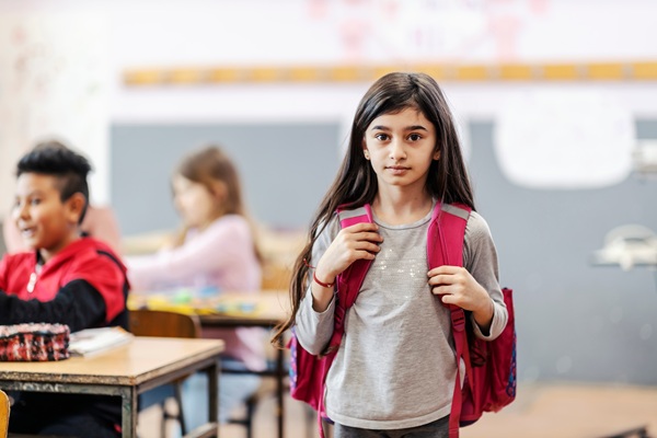 Young girl at school wearing backpack