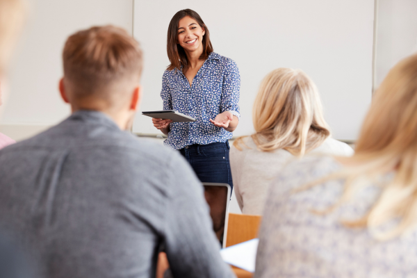 Teacher with a tablet smiling at mature students.