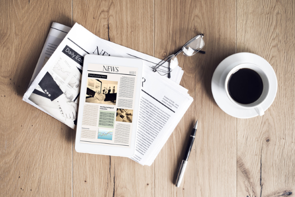 newspaper, glasses, coffee cup and pen on a table