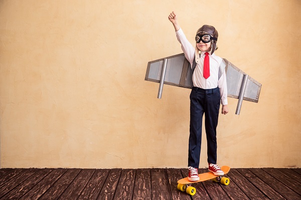 kid on a skateboard wearing airplane wings and pilot glasses