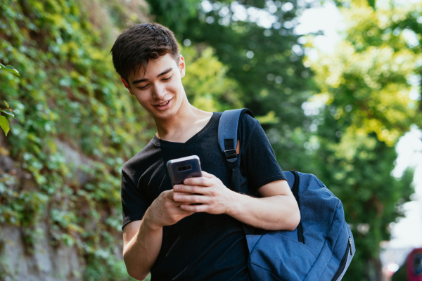 teenager with a backpack looking at his phone