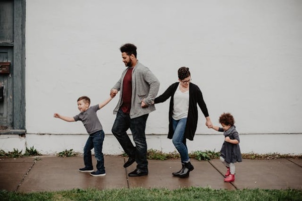 A family of two parents and two small children walking hand in hand