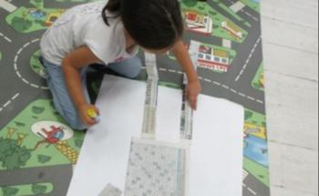 Young learner creating an image of self using pieces of newspaper