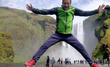 Teacher jumping for joy in front of a the beautiful Icelandic waterfall Seljalandsfoss.