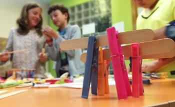 Students smiling and discussing their work as they  build structures with pegs and lolly sticks.