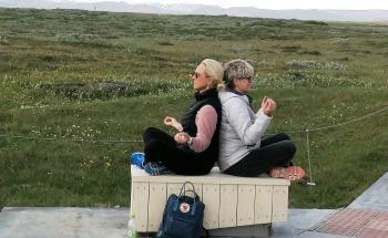 Two teachers practise meditation with icelandic scenery behind.