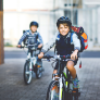 Two boys on bikes wearing helmets and back bags